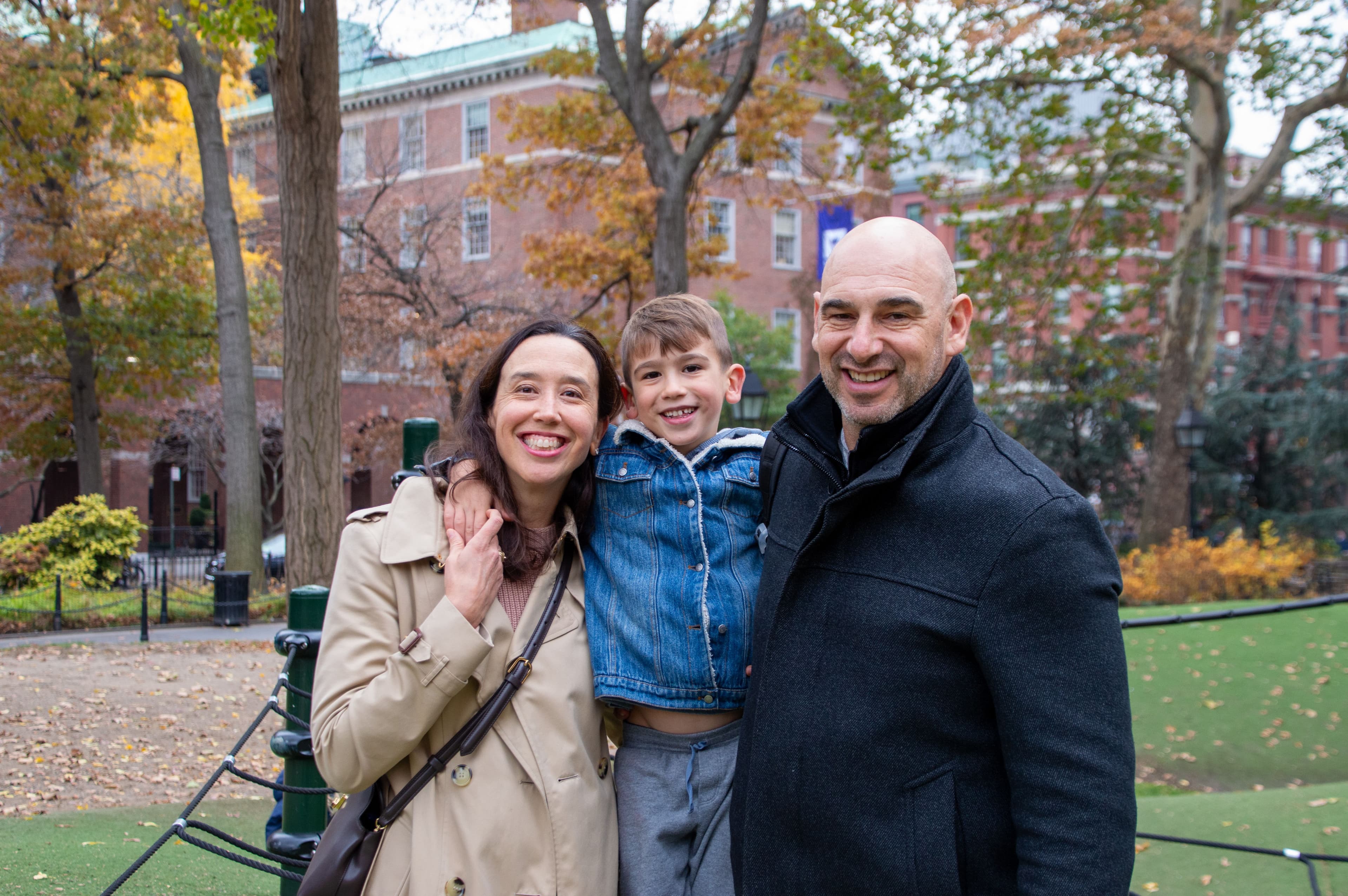A family stands together in front of Washington Square Park's Play Hills in the fall.