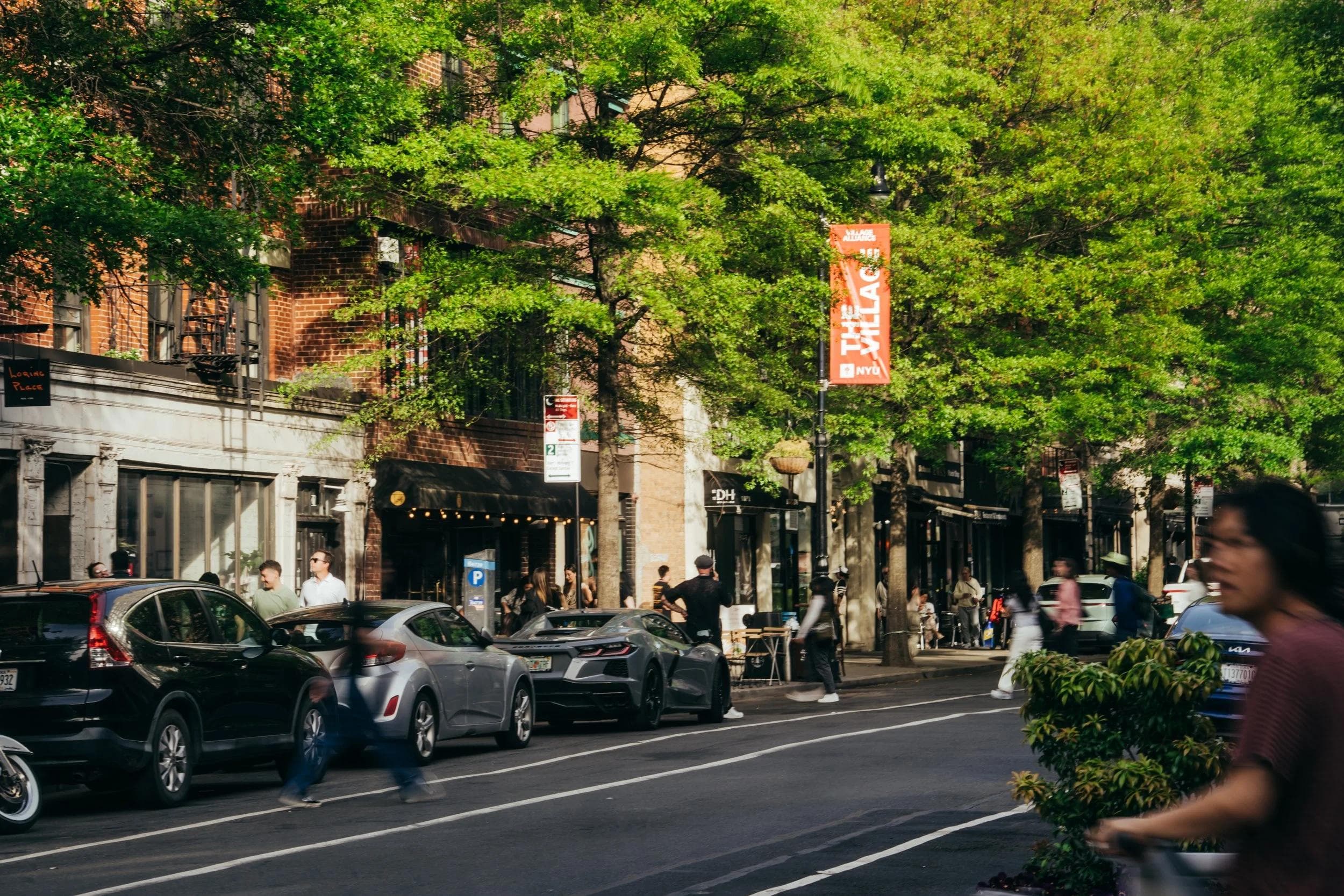 A busy street in New York City with a Village Alliance banner.