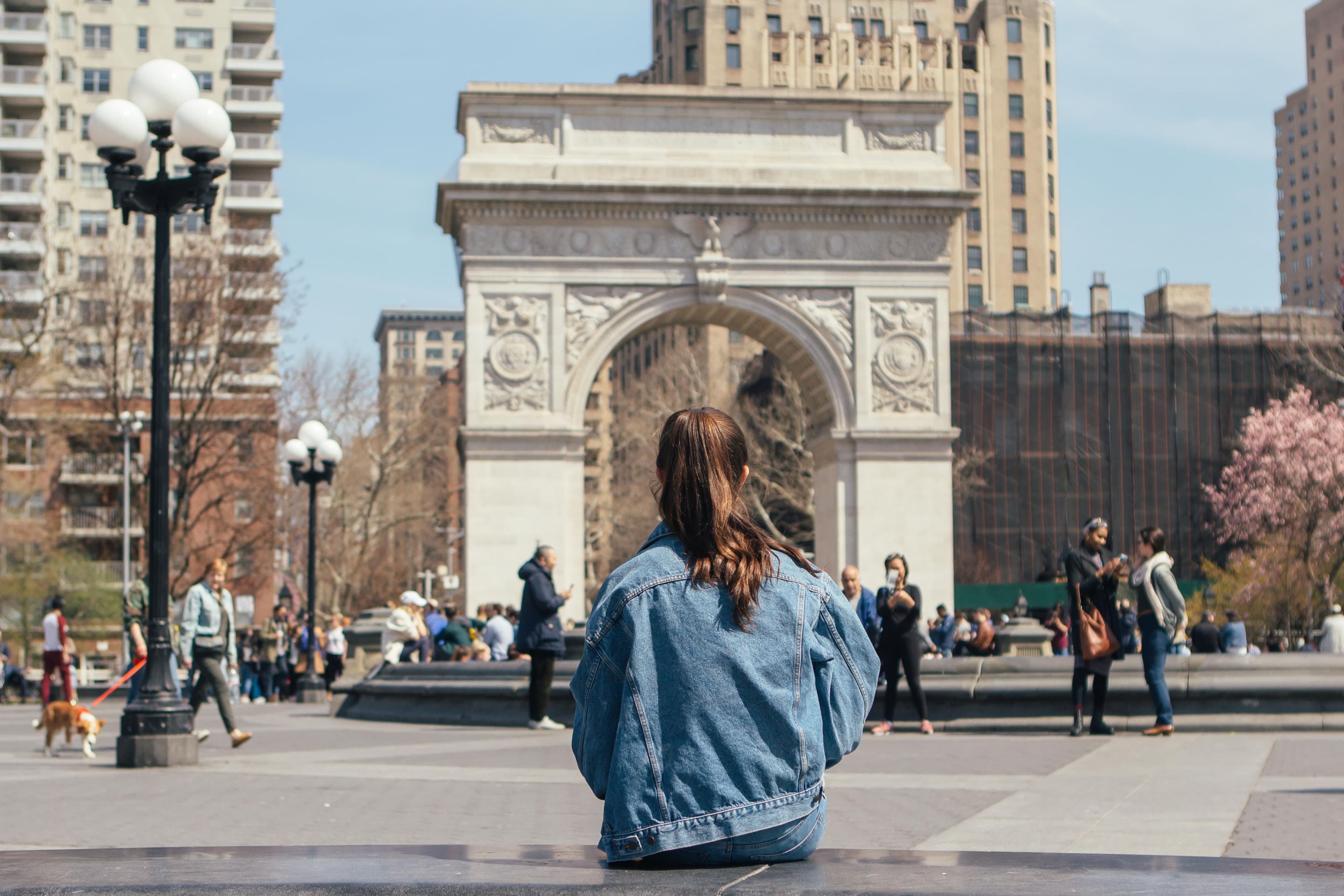 Woman sitting on a bench looking at the arch in Washington Square Park