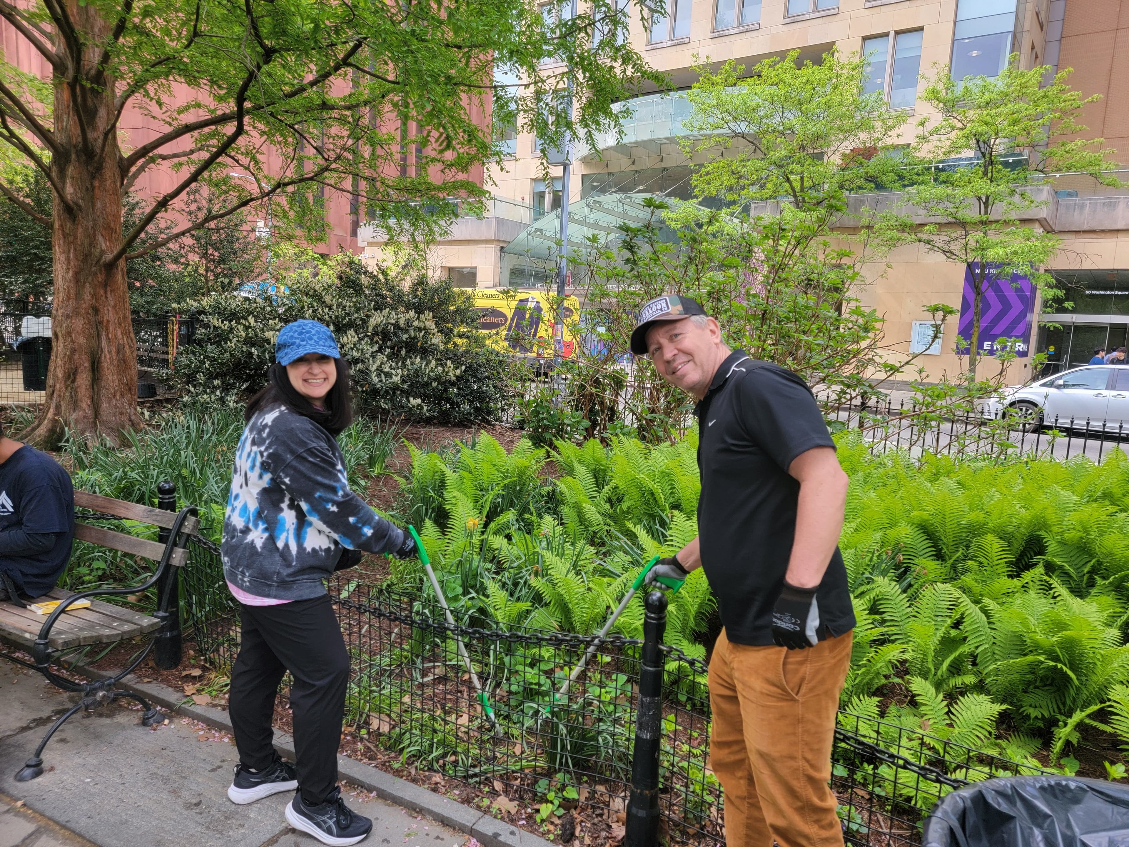 Two volunteers hold trash grabbers in Washington Square Park.